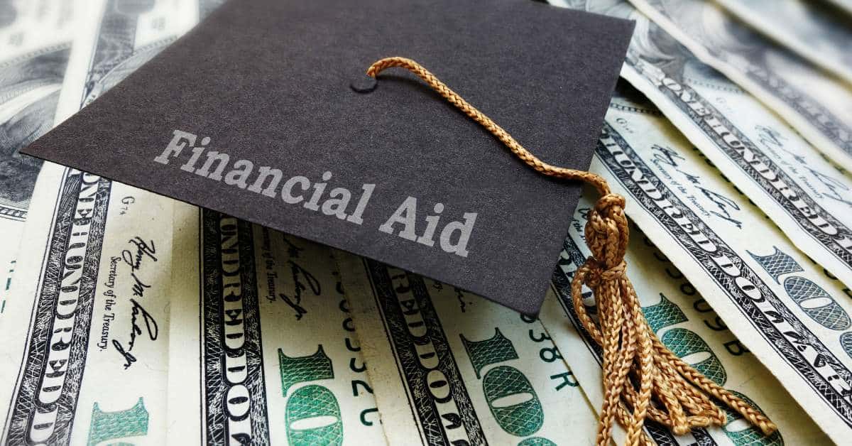A graduation cap with the words "Financial Aid" sitting on top of $100 bills.