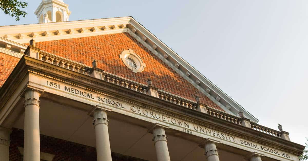 The roof of a brick building with a sign on the front that reads "Georgetown University"