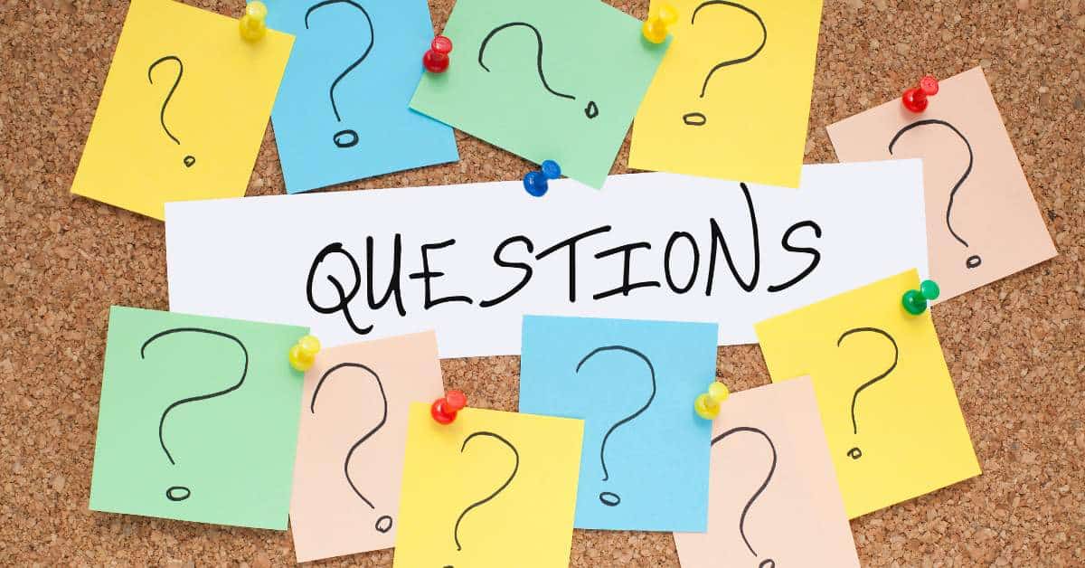 The word "questions" written on a piece of paper with colorful sticky notes surrounding it.
