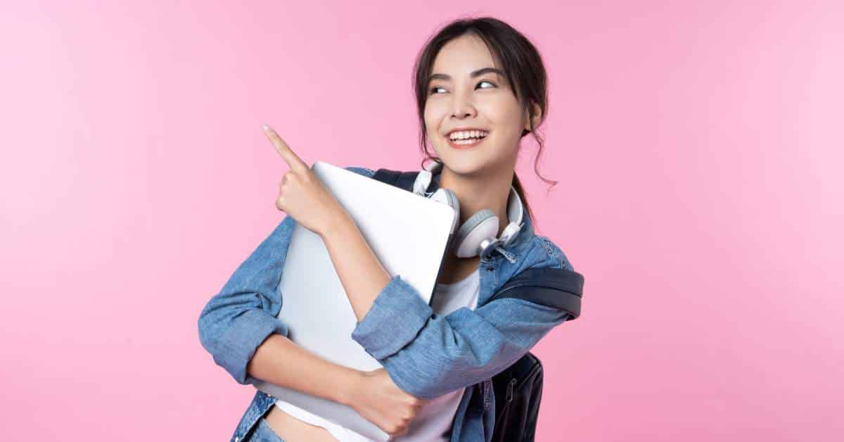Excited girl holding her laptop and pointing skyward