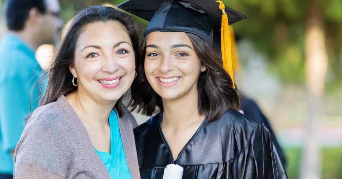 Mom hugging her daughter who is wearing a graduation cap and gown