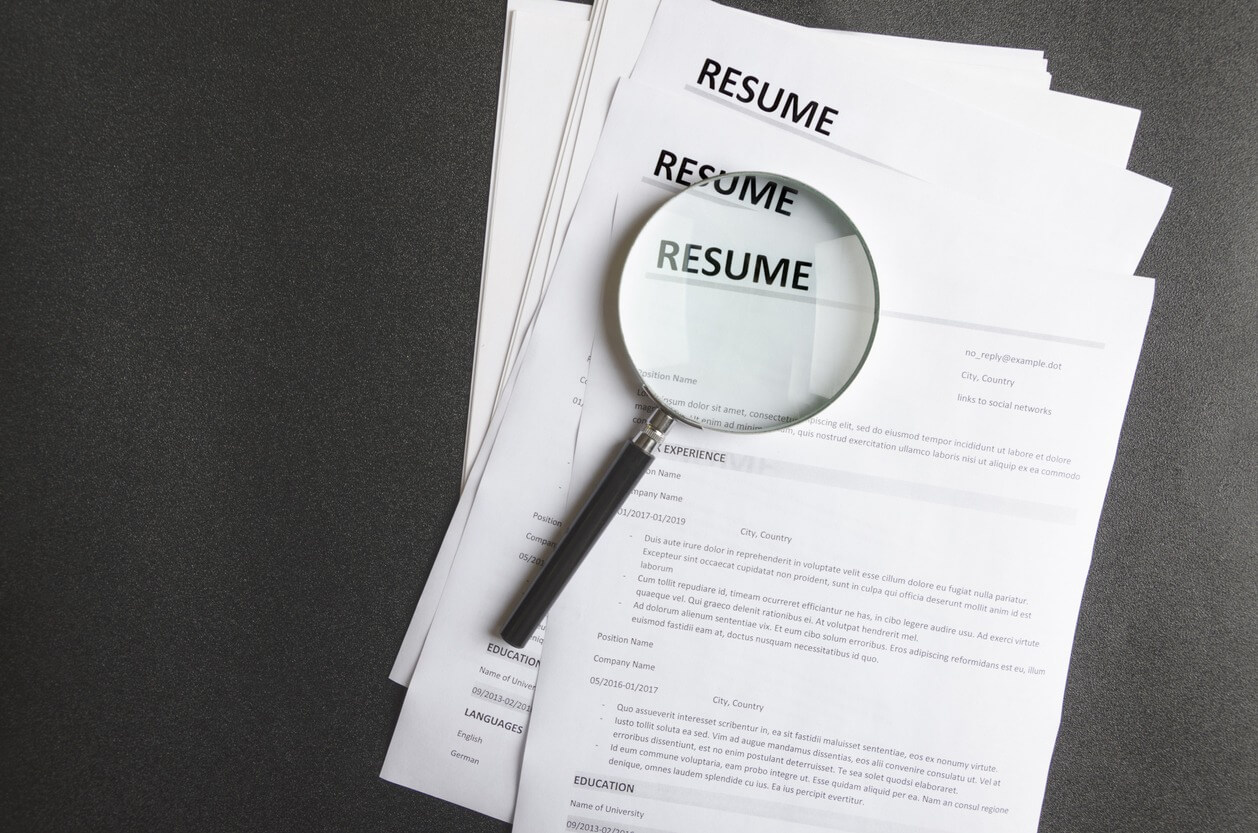 Recruiter`s workplace, pile of resume examples,hand holding magnifier,Concept of analyzing information about new employees