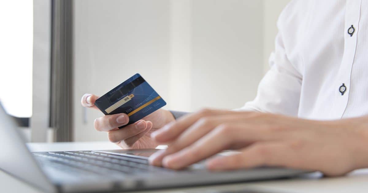Woman Looking at her credit card while typing on her keyboard.