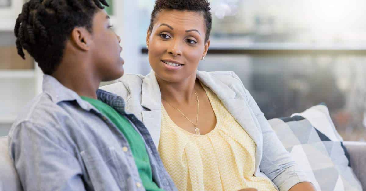 African-American son talking to his mother while sitting on a couch