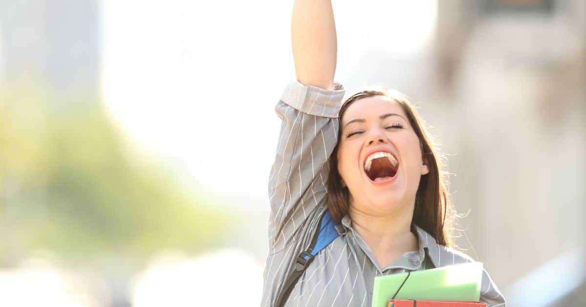 Excited female teen throws her hand in the air and exclaims in excitement