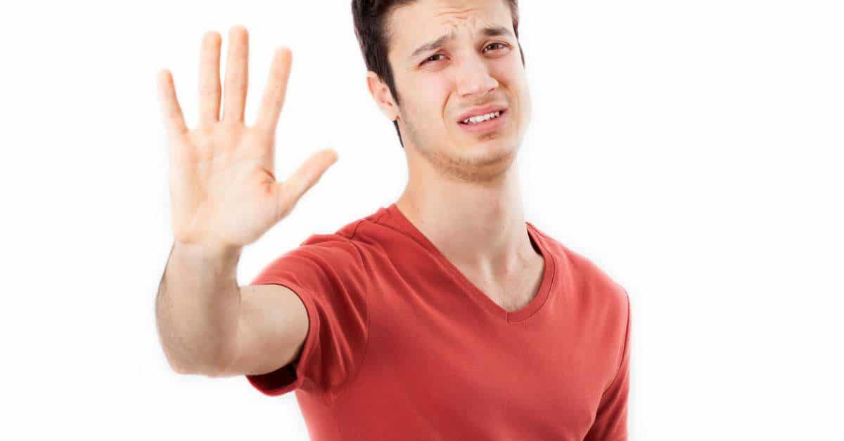Young man holding out his hand in a "stop" motion