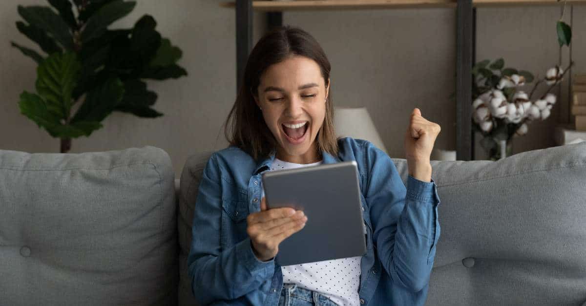 Young woman holding a tablet and exclaiming in excitement