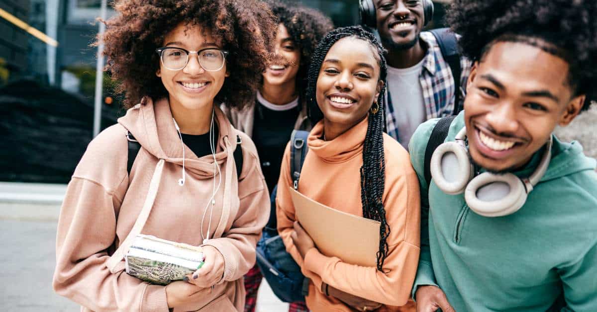 Group of college students holding notebooks and smiling at the camera