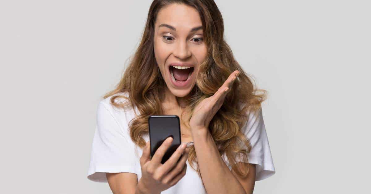 Teenage girl exclaiming while looking at her cell phone