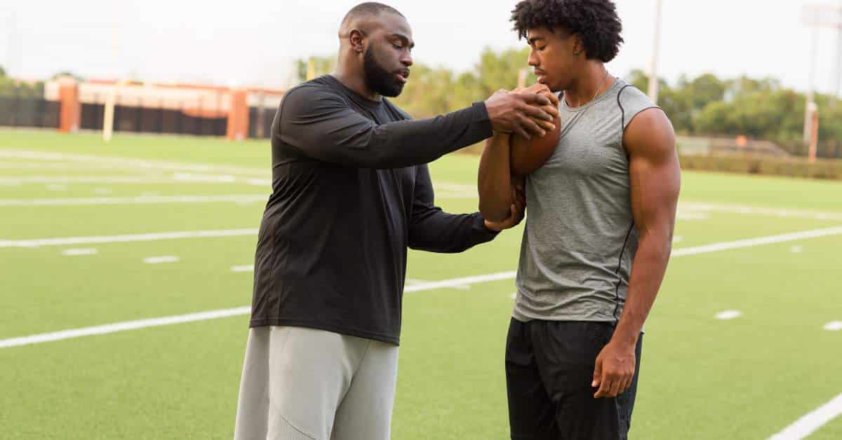 Football coach showing football player how to hold the football properly
