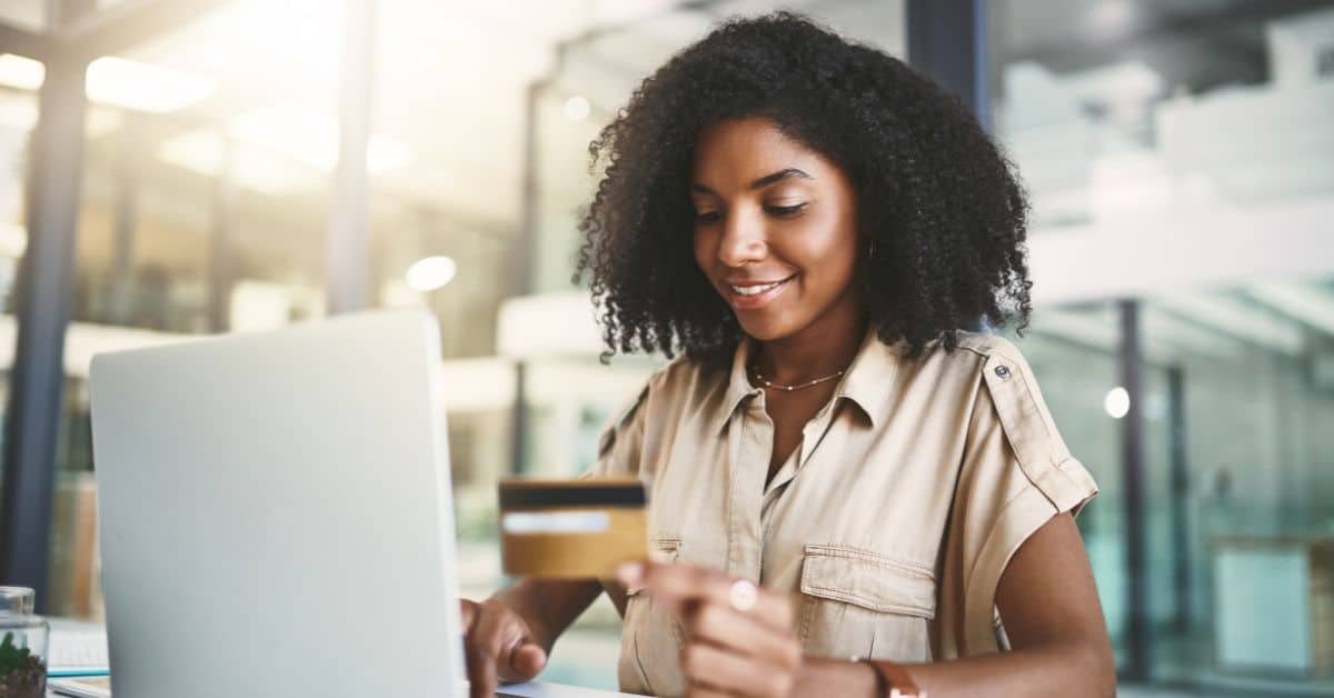 Teenage girl holding a credit card at a computer