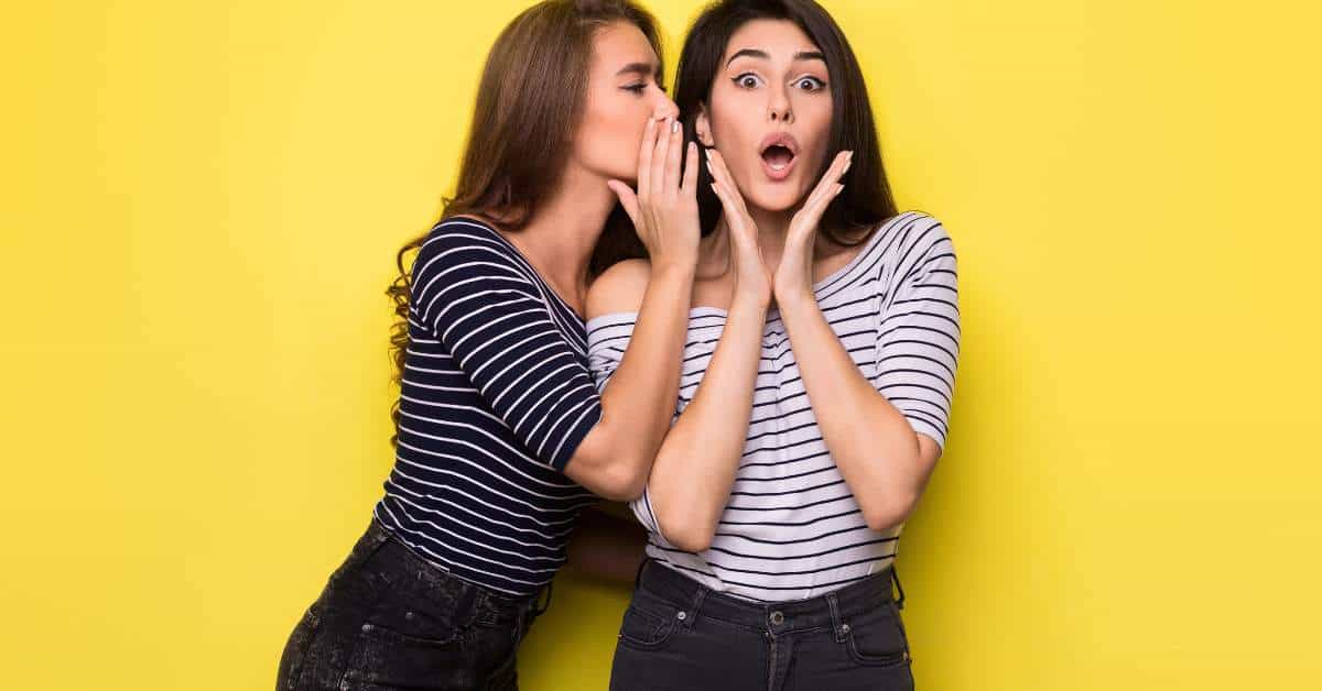 One woman whispering a secret to another woman.