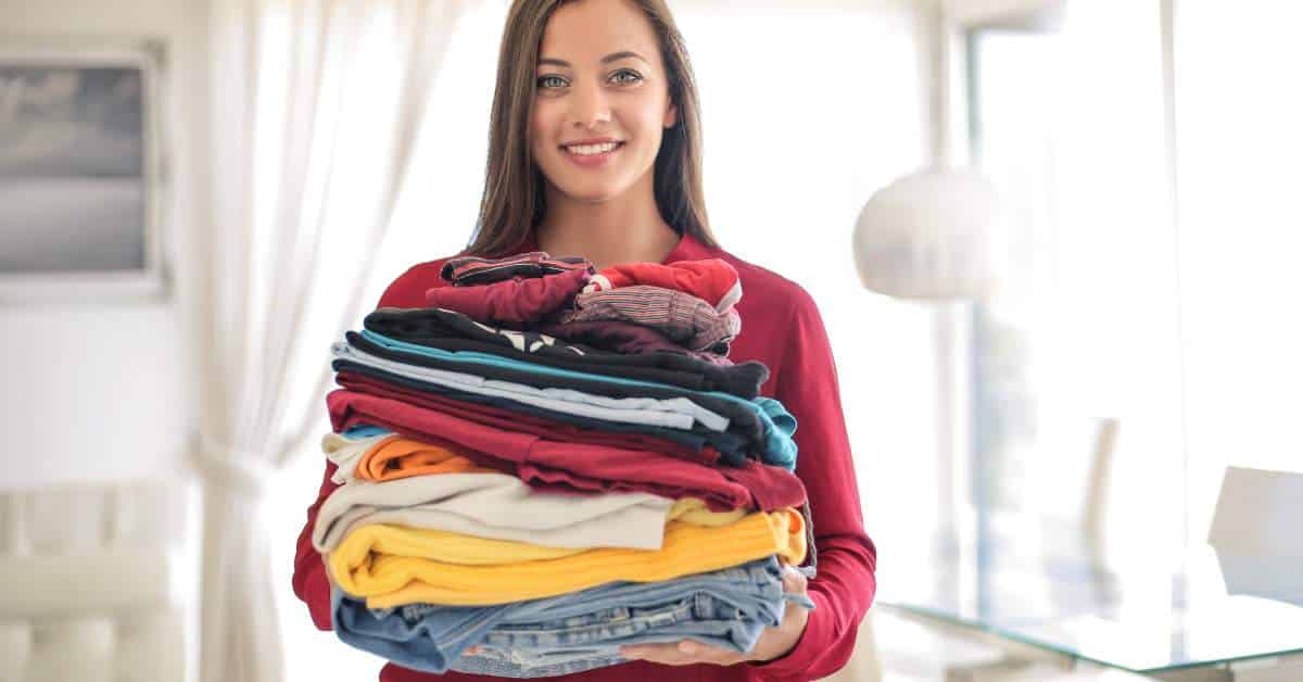 Teen girl holding a stacked pile of laundry