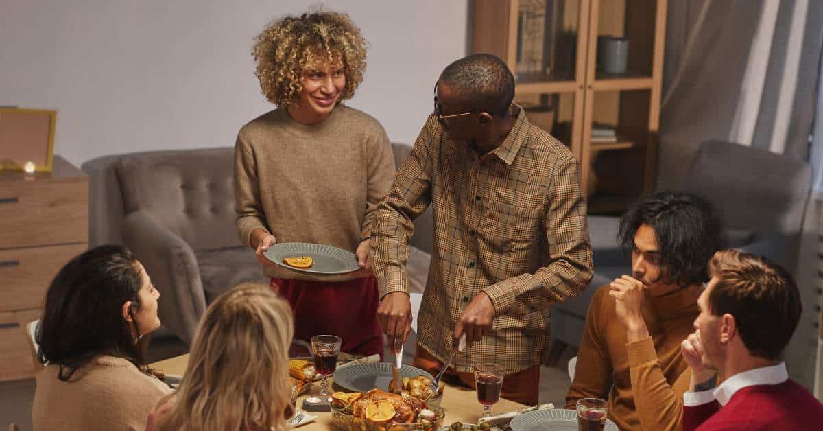 Six people around the Thanksgiving table. One person is serving food.