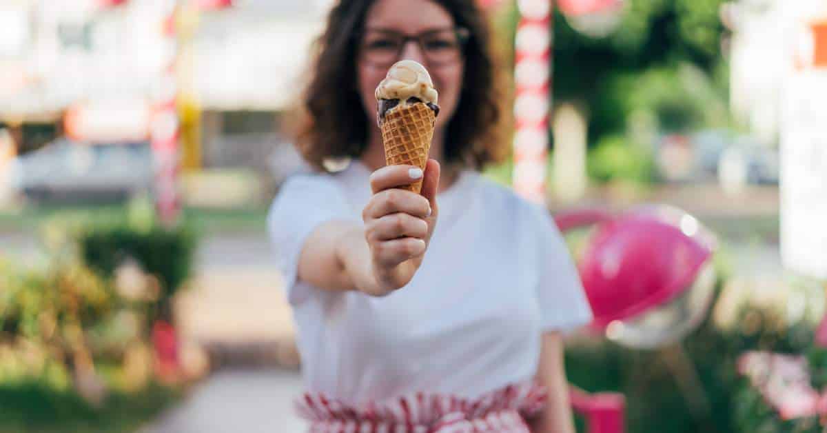 Woman handing an ice cream cone to the person behind the camera